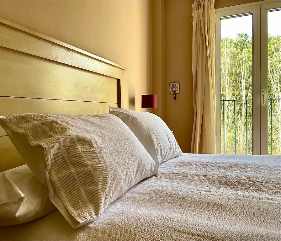 1 dormitorio con 1 cama con sábanas blancas y ventana en La Almenara, en Aracena