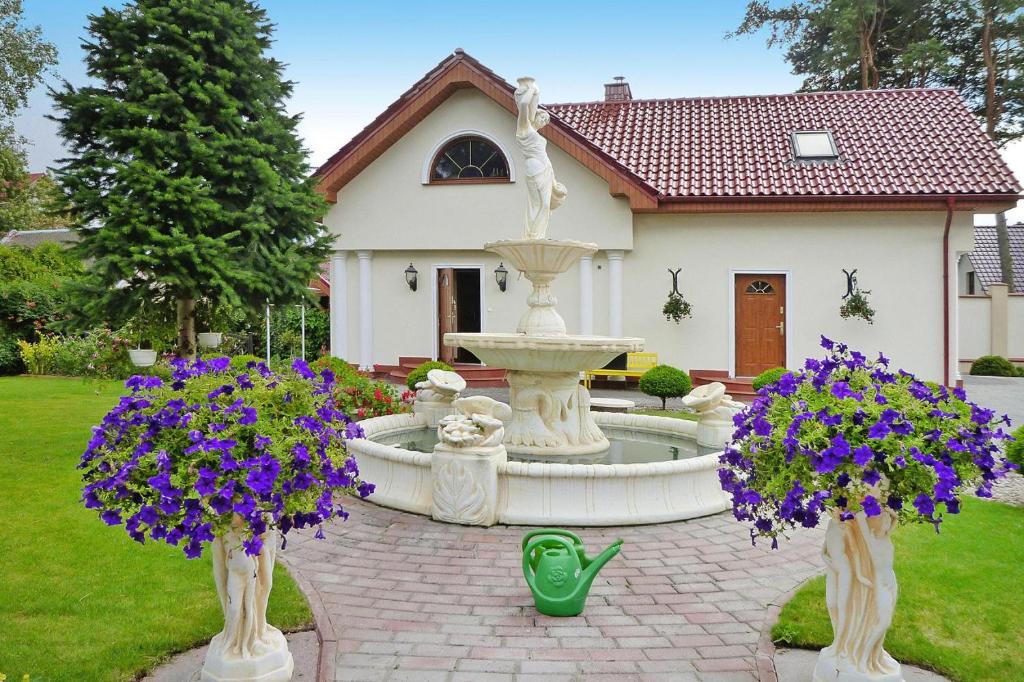 a fountain in front of a house with purple flowers at holiday home, Swibno in Świbno