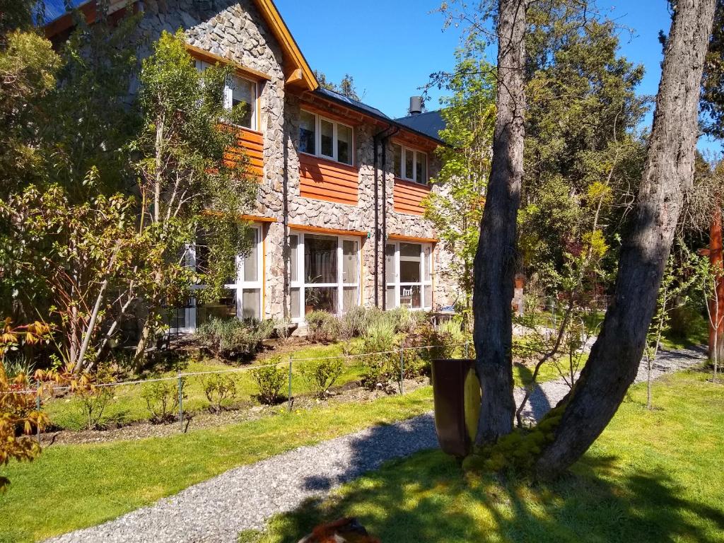 una casa de piedra con árboles delante de ella en Apartamentos Bajo Cero en Villa La Angostura