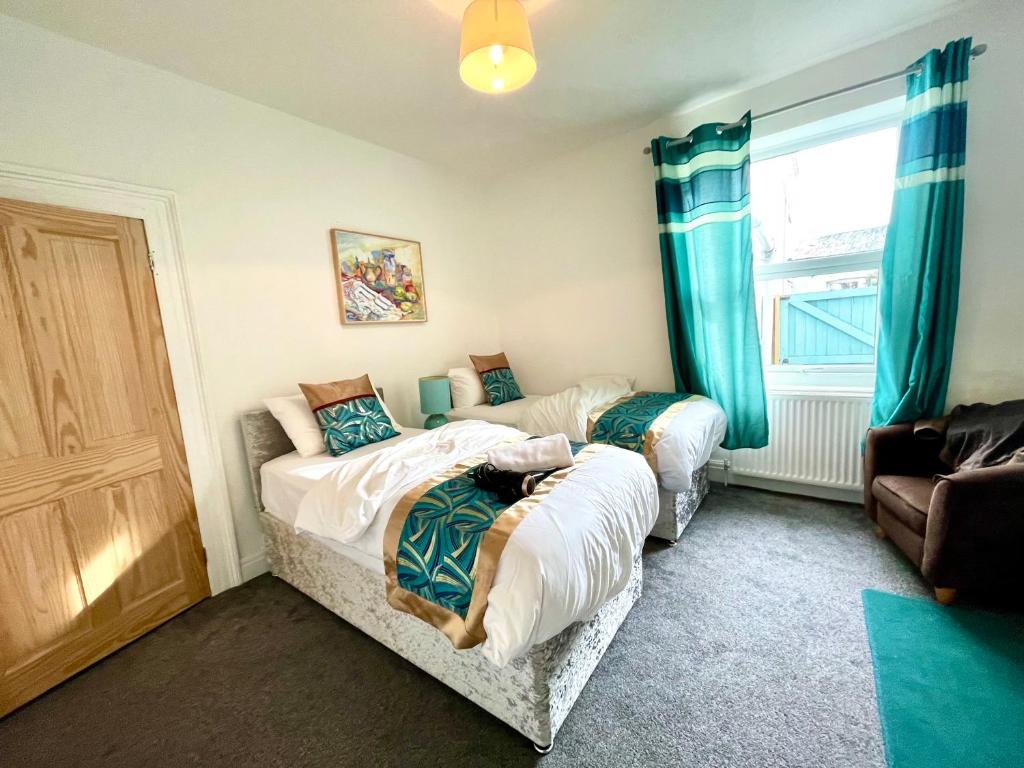 two beds in a room with blue curtains at 3 bedroomed house for up to 7 people, close to The Hoe, Barbican & City Centre in Plymouth