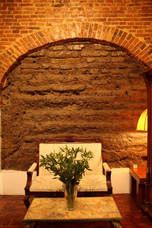 una pared de ladrillo con un sofá y un jarrón sobre una mesa en El Serafin Hotel Boutique, en Querétaro