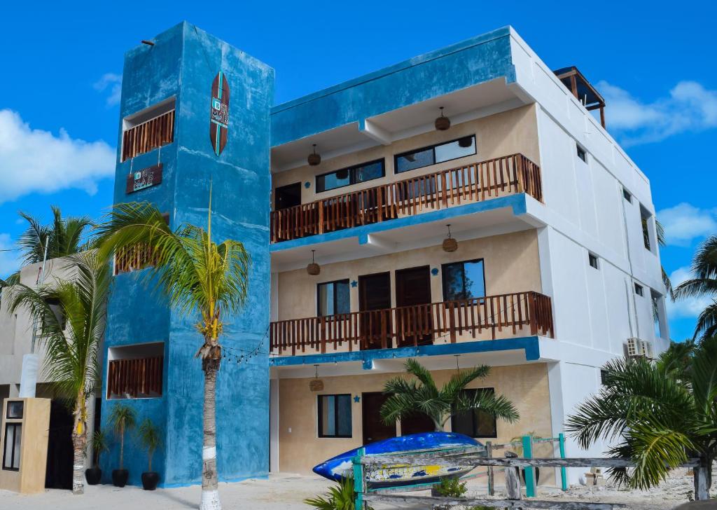 a building on the beach with a palm tree in front at Apartamentos Del Mar El Cuyo in El Cuyo