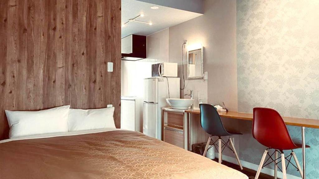 a small room with a bed and two chairs at HYGGE Biimata in Nago