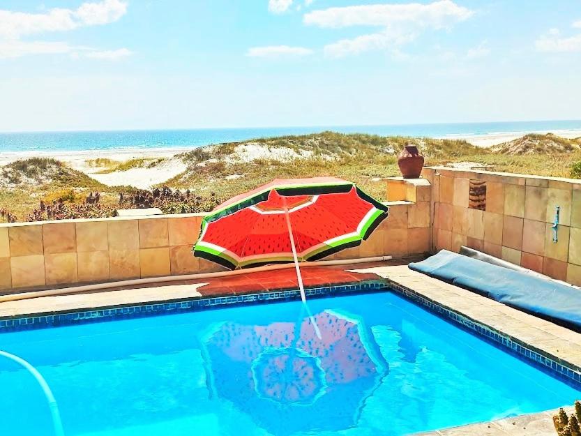 - une piscine avec un parasol, une chaise et un sidx sidx dans l'établissement 14 Penguin Place, Melkbosstrand, à Melkbosstrand