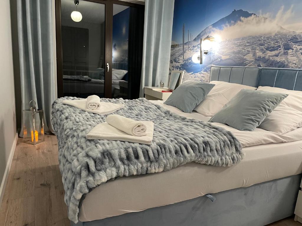 een slaapkamer met een groot bed en handdoeken bij Apartament Silence Karpatia Resort Tanzanit in Karpacz