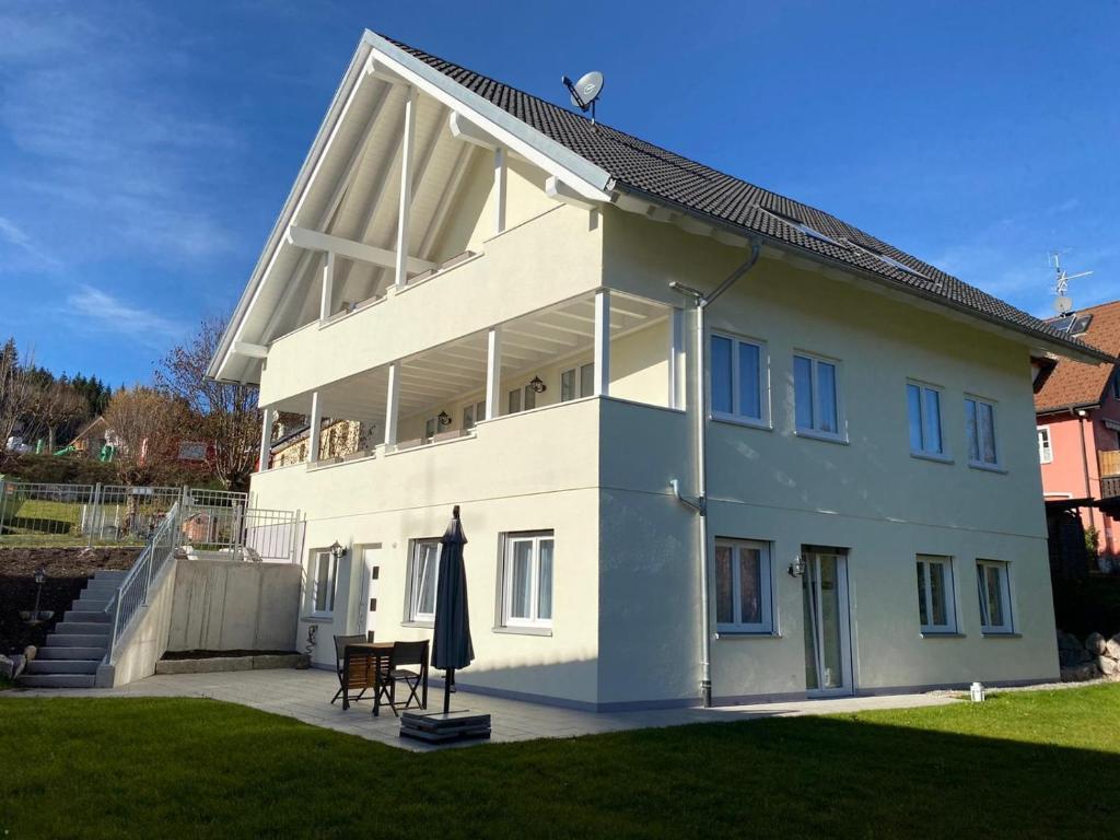 uma grande casa branca com um guarda-chuva no quintal em Steppacher Ferienappartements em Friedenweiler