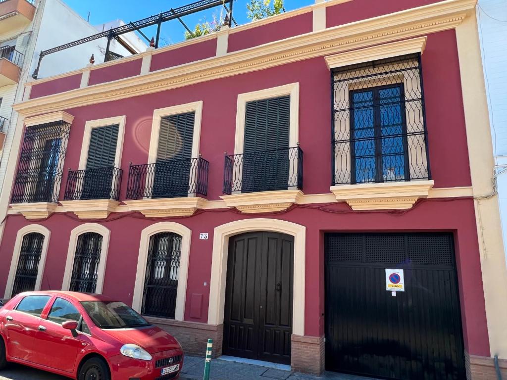 czerwony budynek z czerwonym samochodem zaparkowanym przed nim w obiekcie Teodosio Apartment FREE PARKING & CENTRAL AC w Sewilli