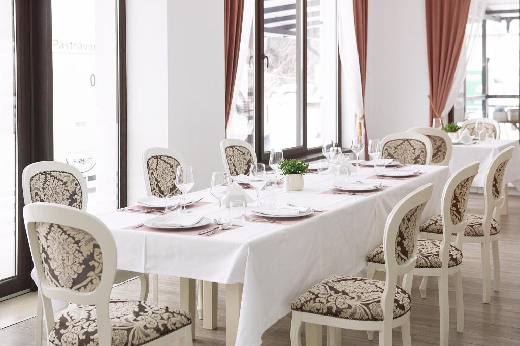 a white table and chairs with plates and wine glasses at Complex Pescăresc Gura Repezii Borșa in Borşa