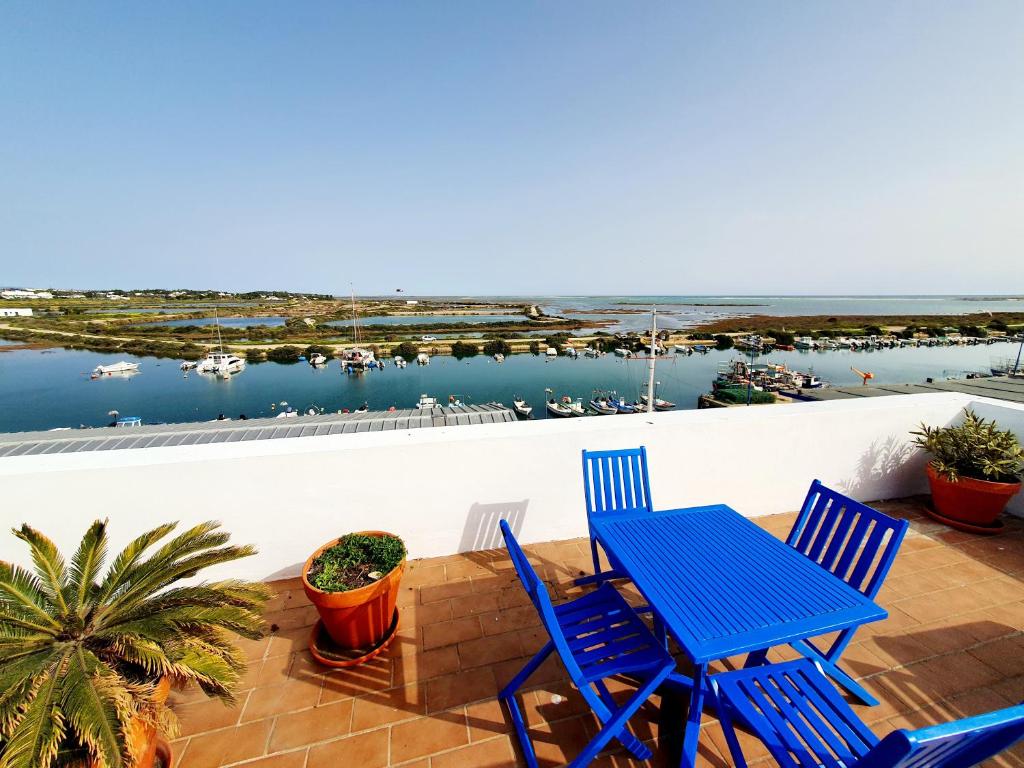 a blue table and chairs on a balcony with a view of a harbor at Apartamento Praia Fuseta 3 - Ria Formosa in Olhão