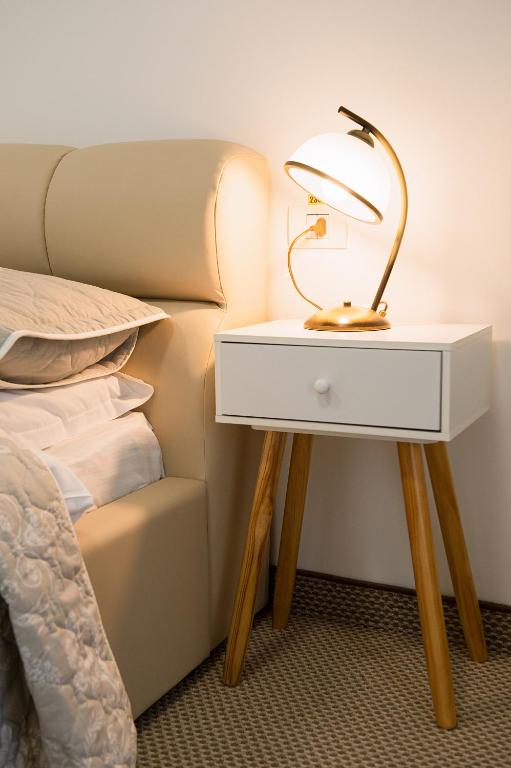 a bedside table with a lamp on it next to a bed at Complex Pescăresc Gura Repezii Borșa in Borşa