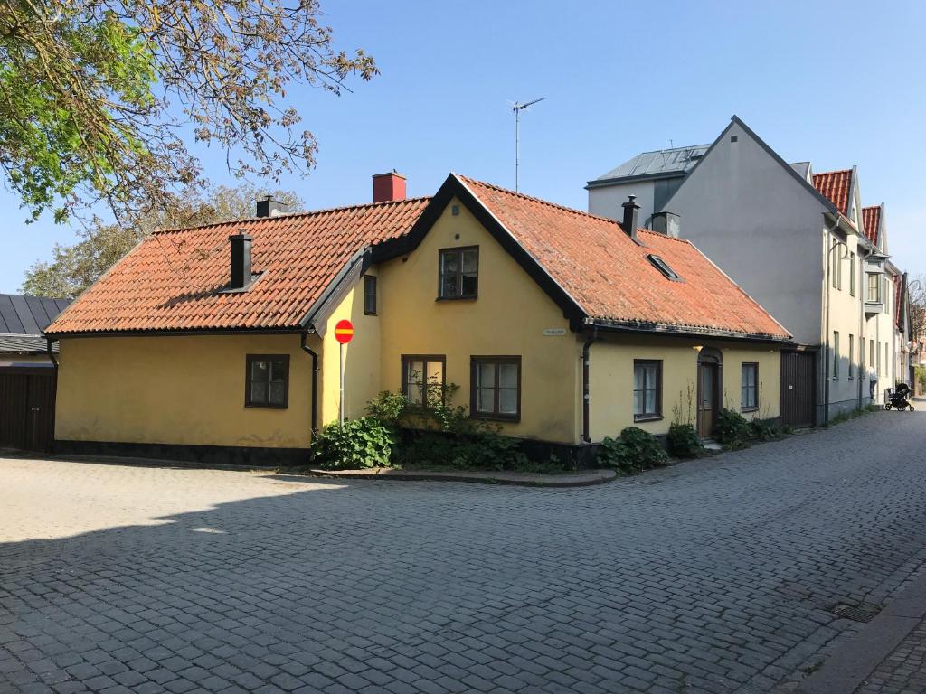 una casa amarilla con un letrero rojo en una calle en Fogelbergs TuB, en Visby