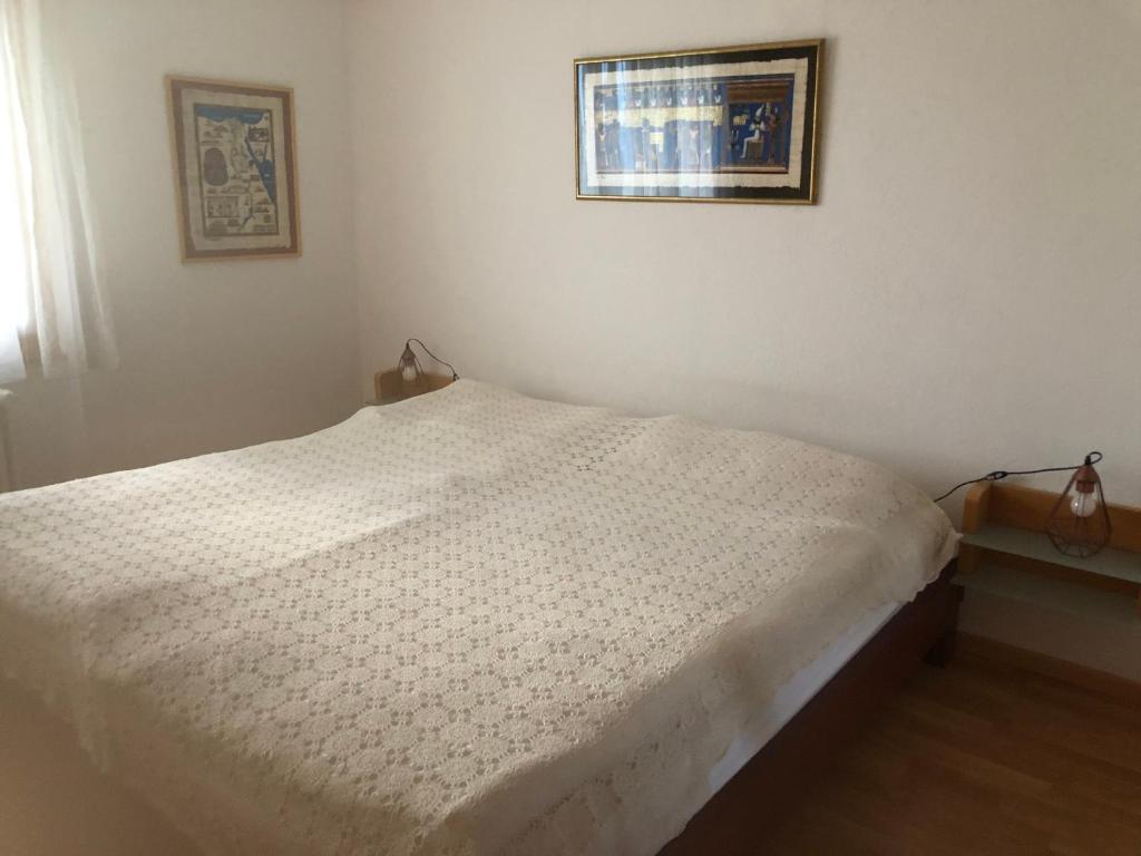 a white bed in a bedroom with a picture on the wall at Albergo Diffuso Porrentruy in Porrentruy