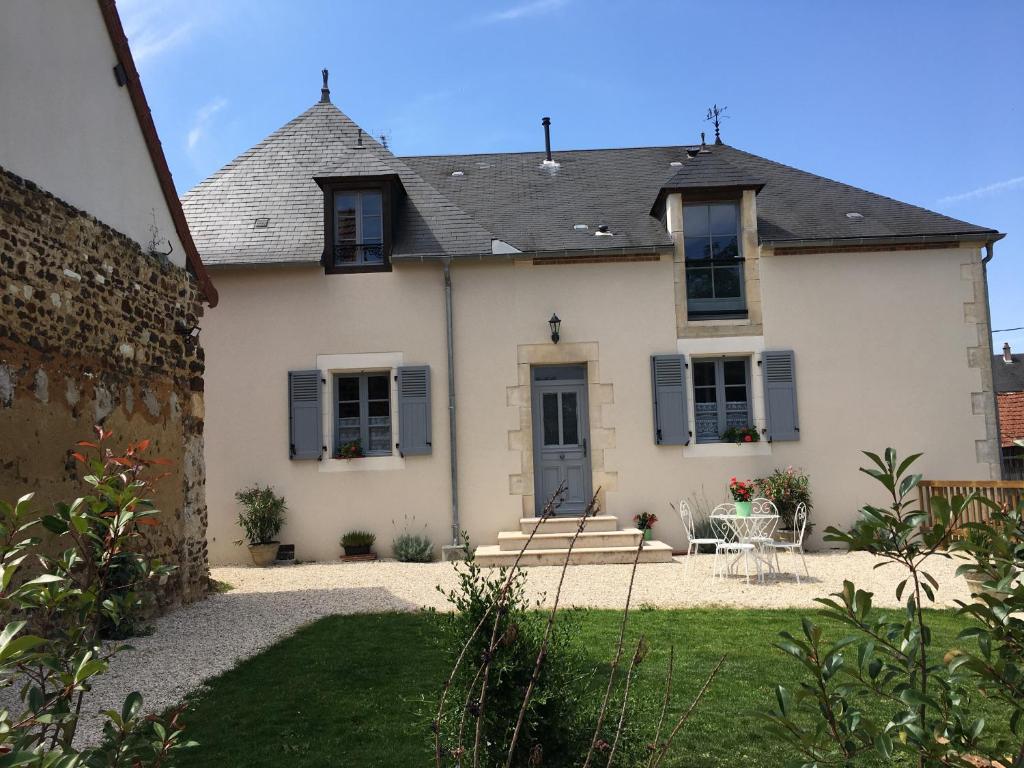 Casa blanca con mesa y sillas en el patio en Gîte de l’enclos, en Menetou-Râtel