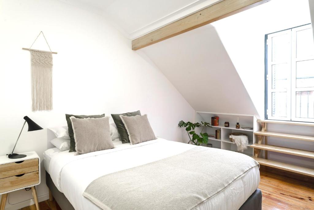 um quarto branco com uma cama e uma janela em City Escape- Apartment In a Quiet Corner of the City em Lisboa