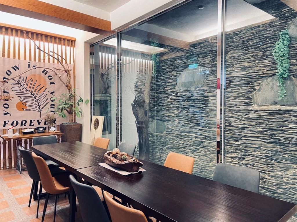 a dining room with a table and a stone wall at Cloud Inn in Hengchun South Gate