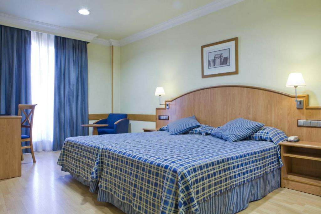 1 dormitorio con 1 cama con manta azul y blanca en II Castillas Madrid, en Madrid