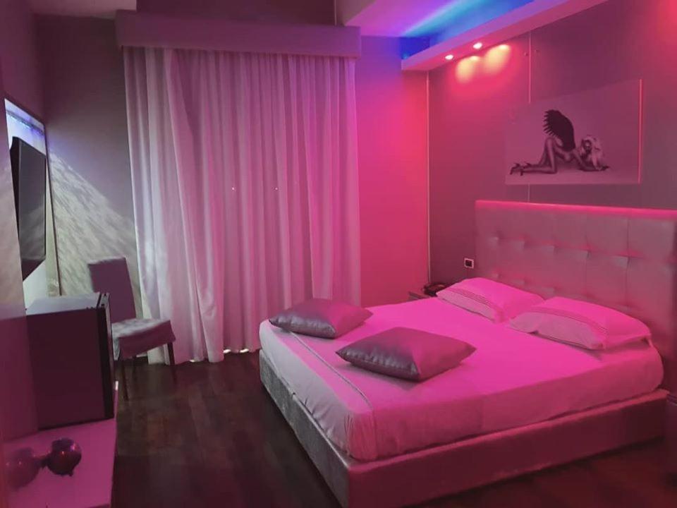 Habitación de color rosa con cama grande y TV. en Hotel La Fayette, en Licola