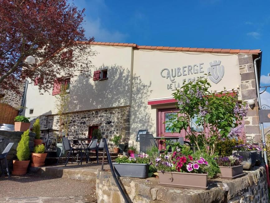 un bâtiment avec des plantes devant lui dans l'établissement Auberge de la Loue, à Vodable