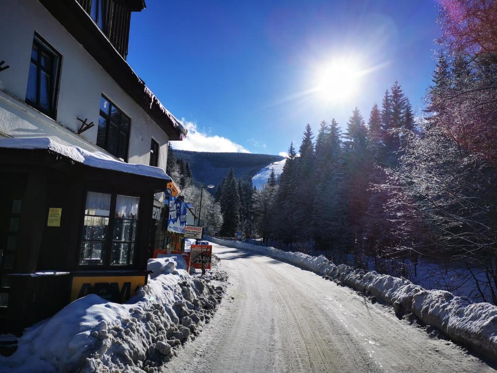 une route recouverte de neige à côté d'un bâtiment dans l'établissement Hostel Fortuna, à Špindlerův Mlýn