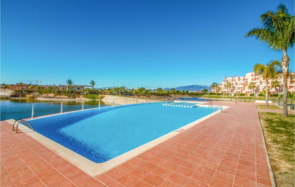 a swimming pool in a resort with palm trees and buildings at Cozy Apartment In Alhama De Murcia With Wifi in Alhama de Murcia