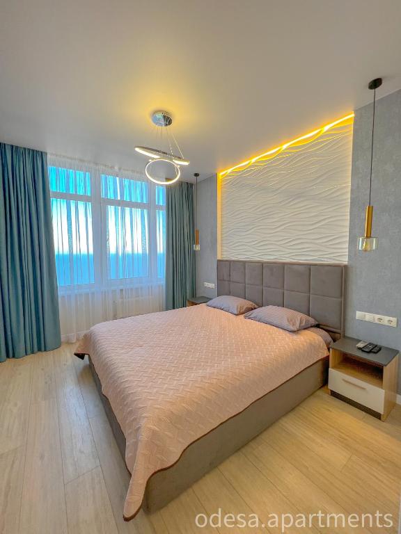 a bedroom with a large bed and some windows at Sea View Sky 15 Apartments in Odesa