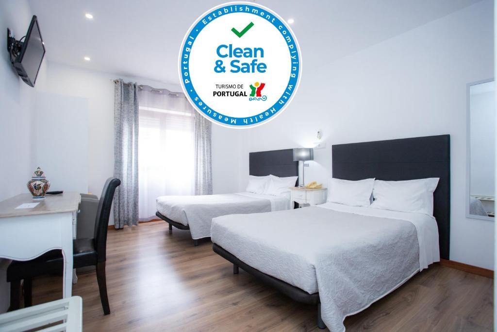 um quarto de hotel com duas camas e uma placa que diz limpo e seguro em Hotel Domus em Coimbra