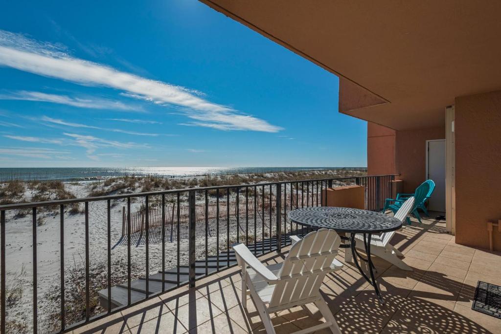 a balcony with a table and chairs and the beach at Gulf Winds 101 in Pensacola Beach
