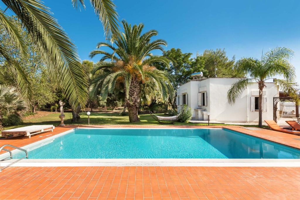 ein Pool vor einem Haus mit Palmen in der Unterkunft Villa with swimming pool Salento - Villa Le Due Sorelle in Ugento