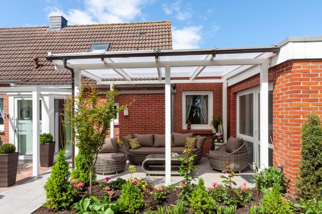 eine weiße Pergola auf einem Backsteinhaus in der Unterkunft Hotel garni NordSeerose Greetsiel in Krummhörn