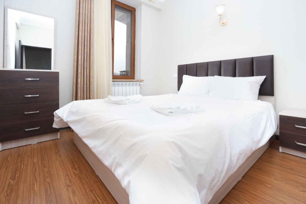 sypialnia z dużym białym łóżkiem i drewnianą podłogą w obiekcie Stay Inn Apartments at Mashtots avenue 33-1 w Erywaniu