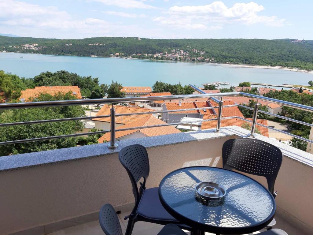 een balkon met een tafel en stoelen en uitzicht op een meer bij Gita Apartmani in Čižići