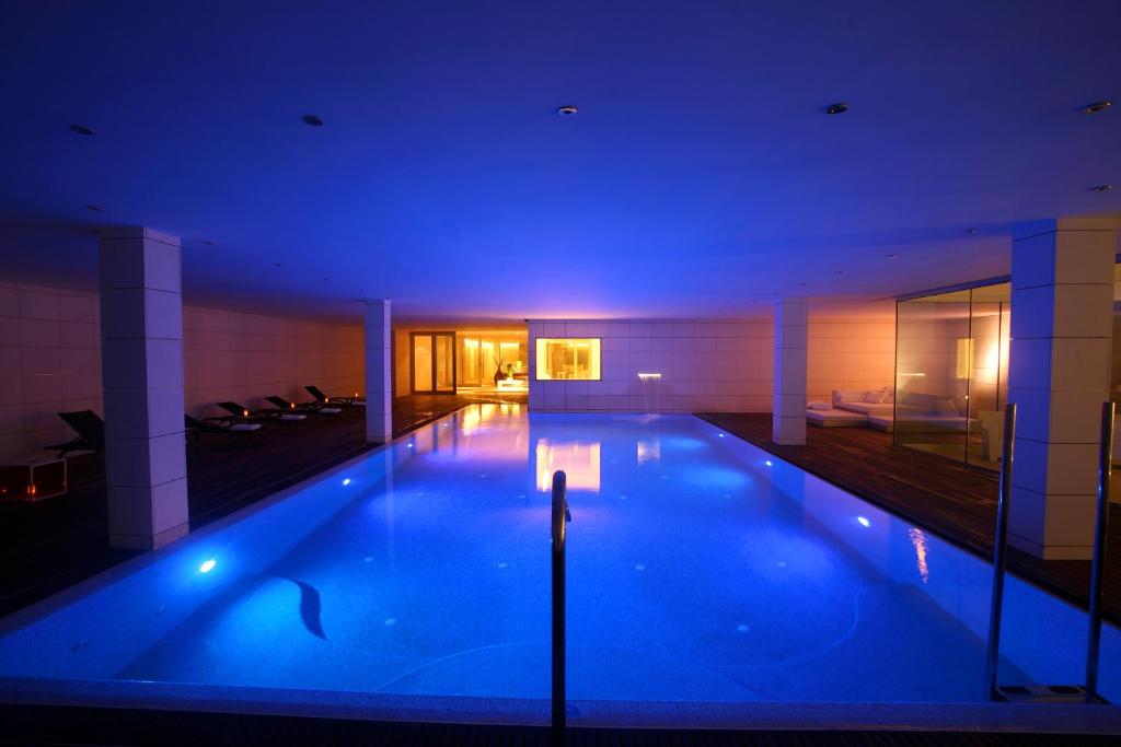 a large swimming pool in a building with blue lighting at Finca Prats Hotel Golf & Spa in Lleida