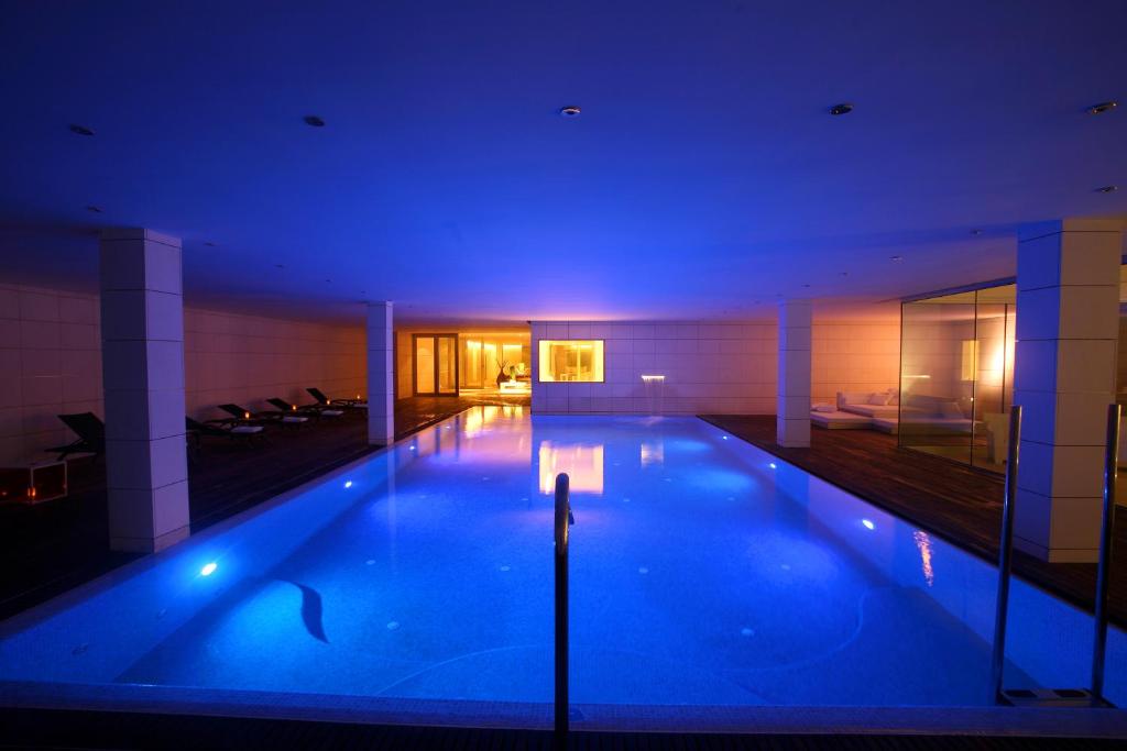 ein großer Pool in einem Gebäude mit blauer Beleuchtung in der Unterkunft Finca Prats Hotel Golf & Spa in Lleida