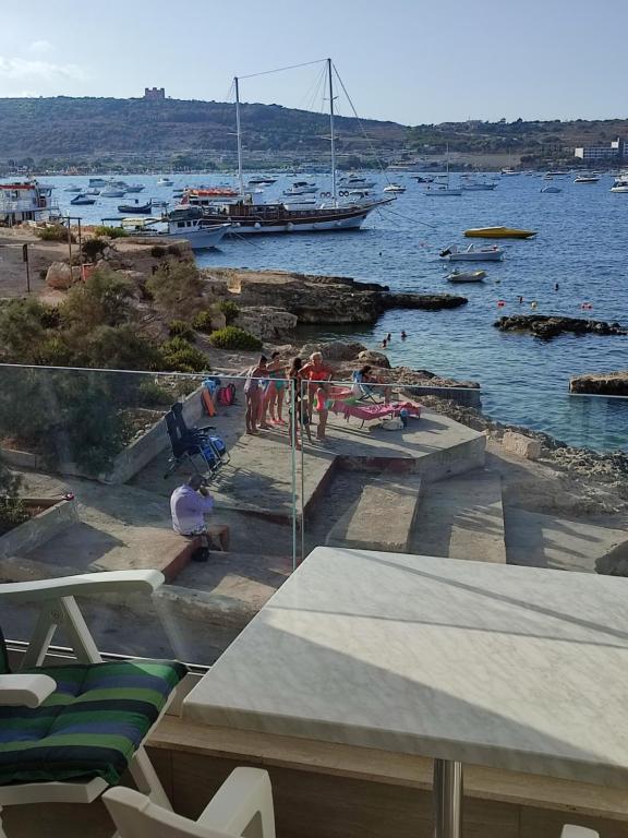 a group of people on a beach with boats in the water at BEACHFRONT with Seaviews Apartment No56 Award Winner Unbeatable Location for Closeness to the Sea Ideal for Guests looking for Winter Spring and Autumn Breaks in Sunny Malta Also Ideal for Coastal Hikers in Mellieħa