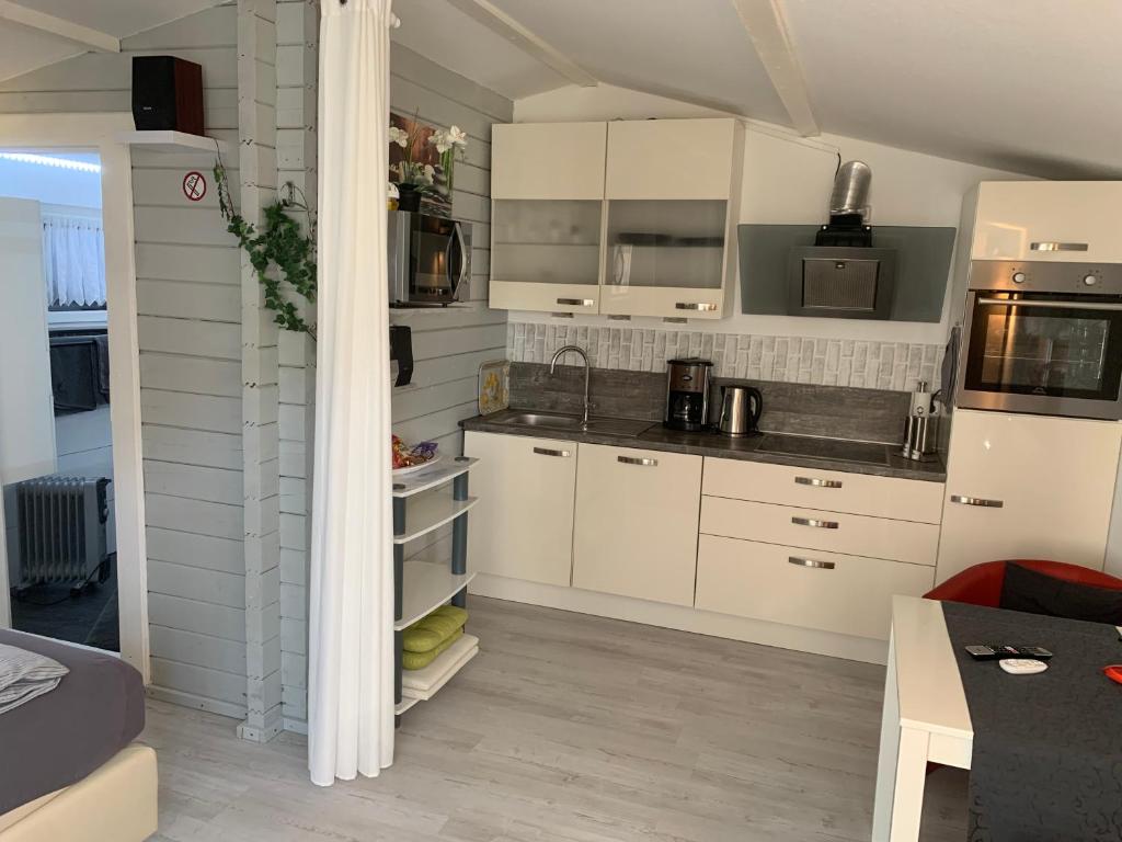 eine Küche mit weißen Schränken und einer Arbeitsplatte in der Unterkunft Holzhaus Leverkusen in Leverkusen