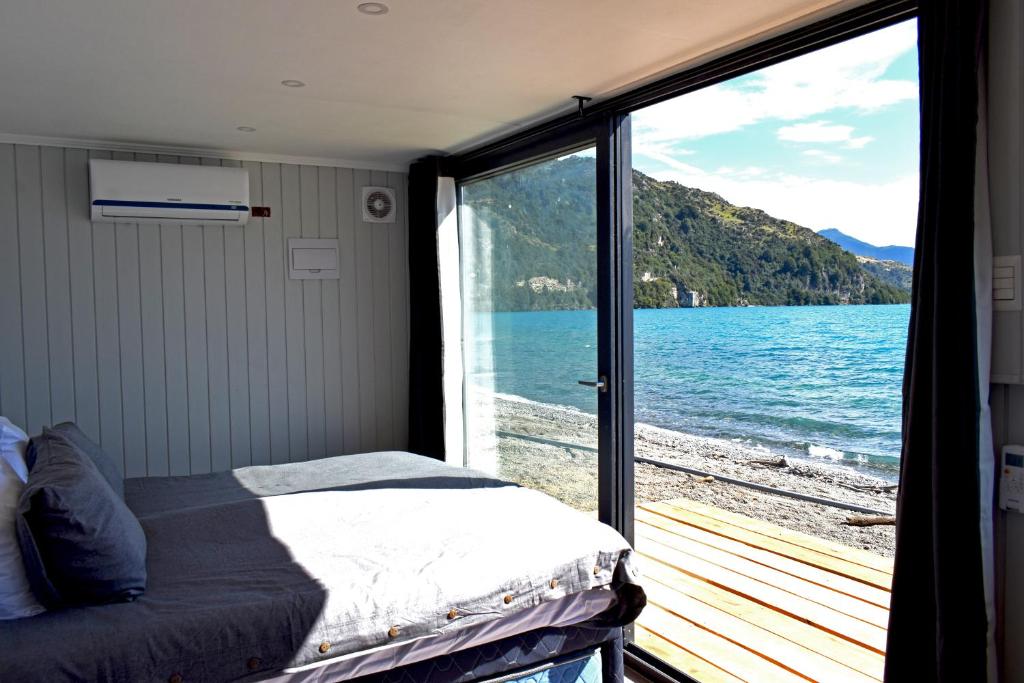 a bedroom with a bed and a view of the water at Chelenko Lodge in Puerto Tranquilo
