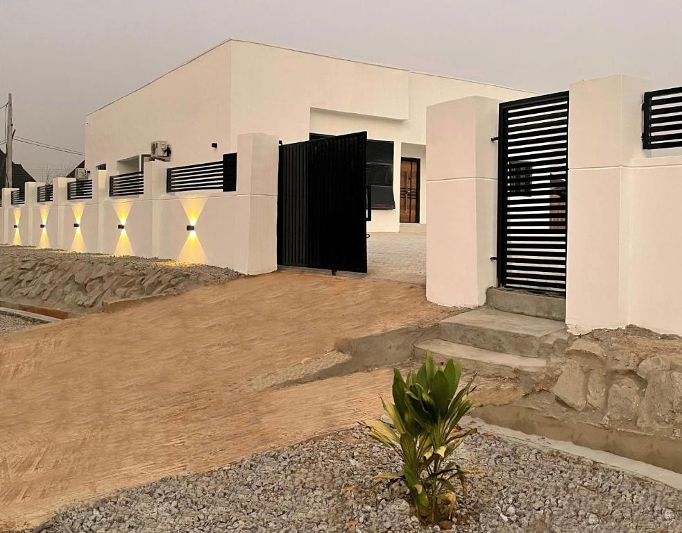 Casa blanca con puertas negras y patio en Blanco Homes Shortlet Apartment Ilorin, en Ilorin