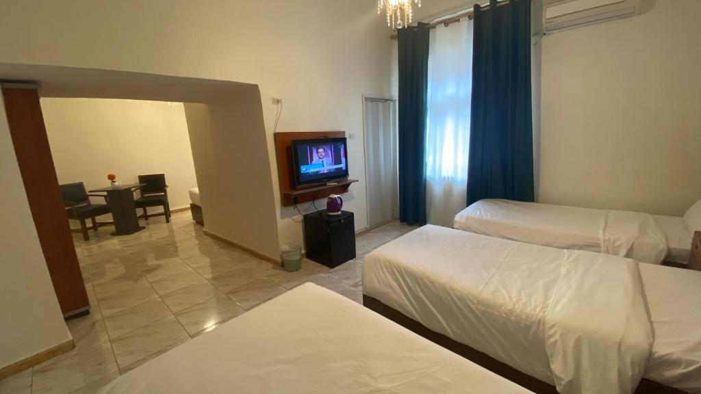 um quarto de hotel com duas camas e uma televisão em New Park Hotel em Amã
