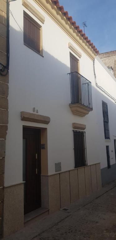 um edifício branco com duas varandas e uma porta em ENTRE TORRES em Jerez de los Caballeros