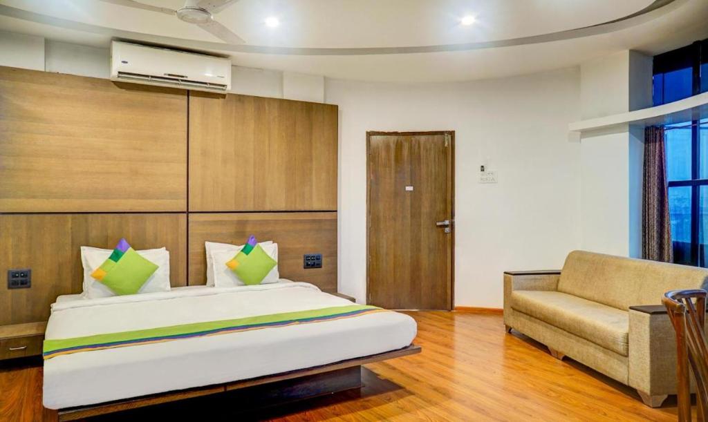 a bedroom with a bed and a couch and a chair at Hotel Shivas Inn in Kolhapur