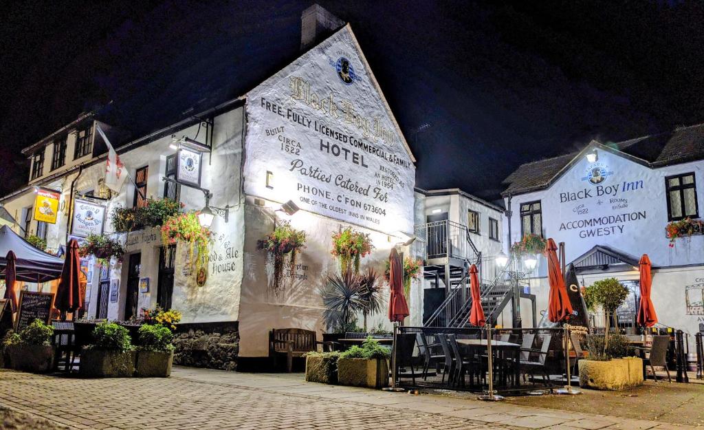 a building with tables and umbrellas in front of it at The Black Boy Inn in Caernarfon