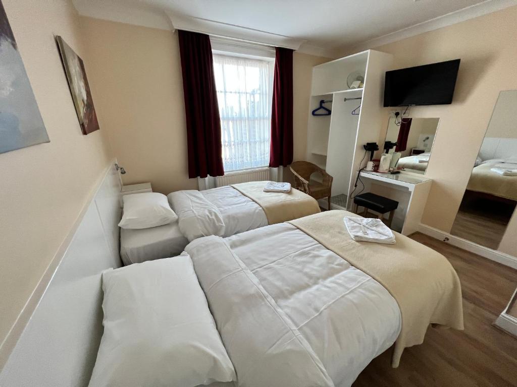 ロンドンにあるメルボルン ハウス ホテルのベッド2台とテレビが備わるホテルルームです。