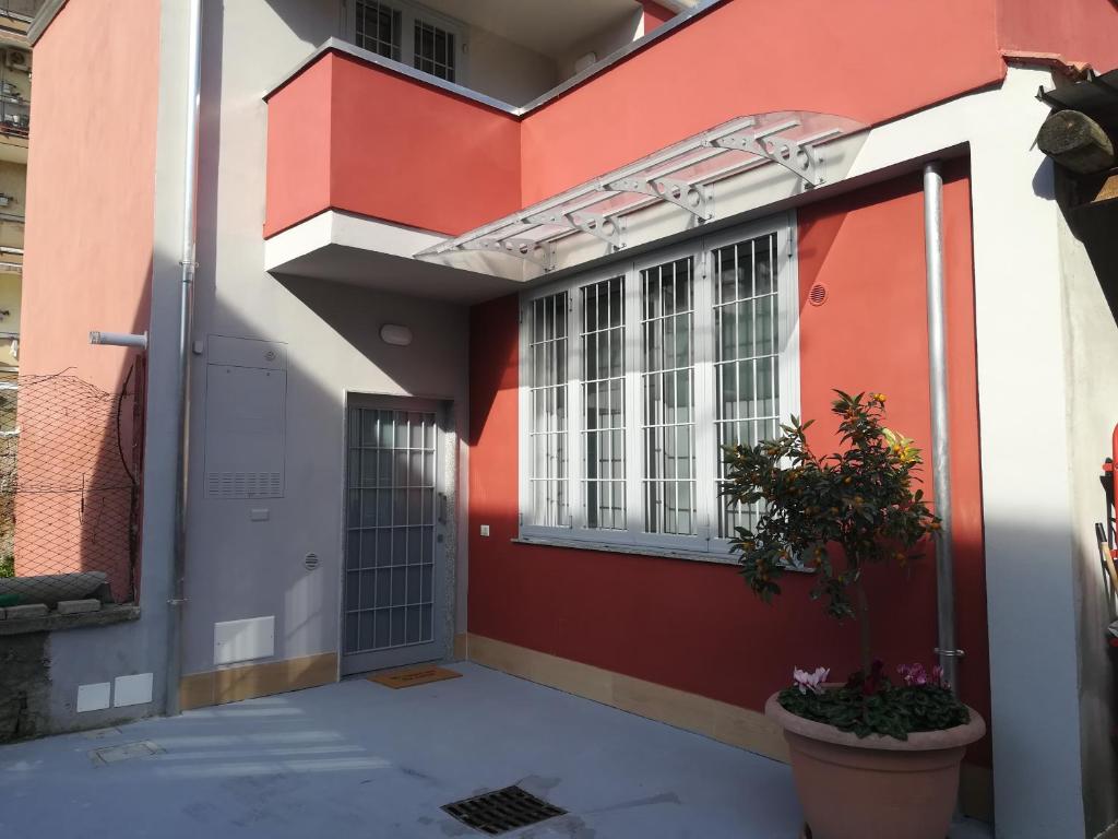 un edificio rosso e bianco con una porta e una pianta di casa mariuccia a San Nicola La Strada