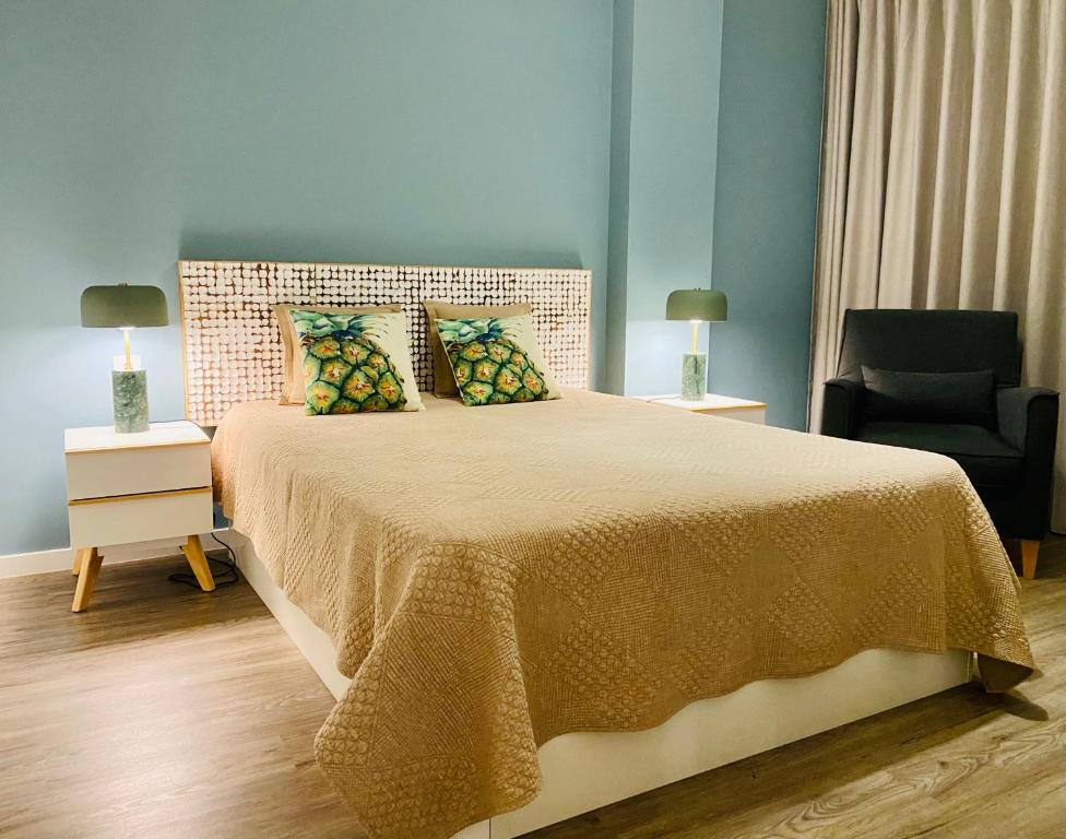 een slaapkamer met een groot bed en een stoel bij Ocean Cliffs Apartments in Funchal