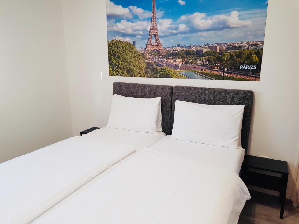 two beds in a room with a picture of the eiffel tower at Mátyás Panzió in Szeged