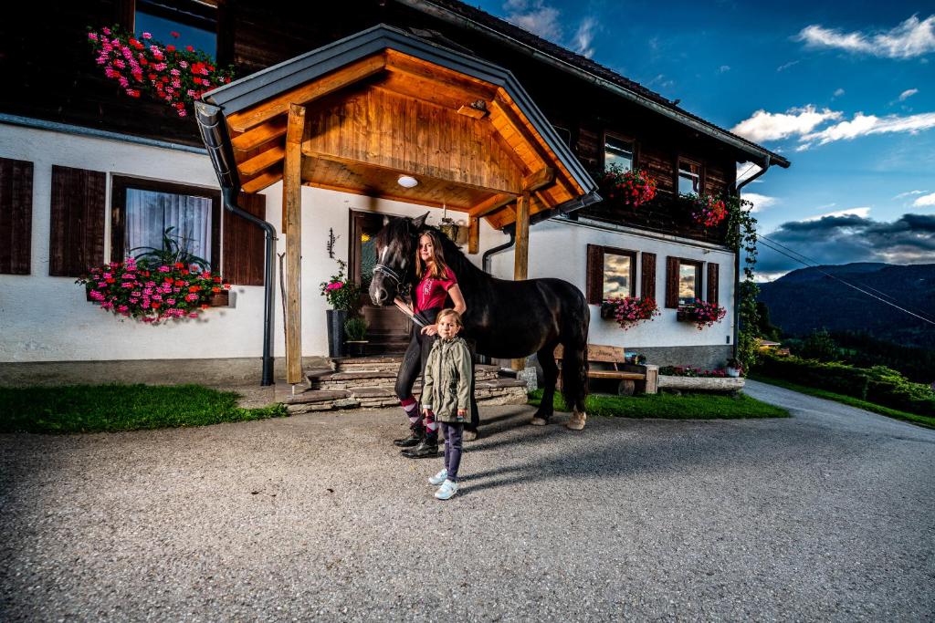 Eine Frau und ein Kind und ein Pferd vor einem Haus in der Unterkunft Rainerhof in Murau