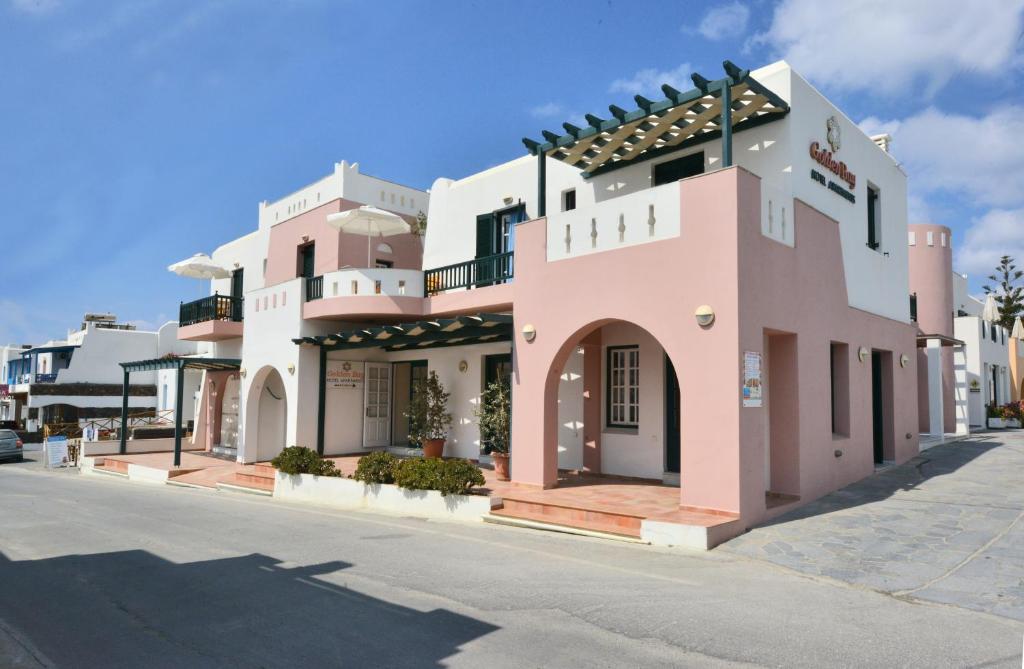 een roze gebouw aan de kant van een straat bij Golden Bay in Agios Prokopios