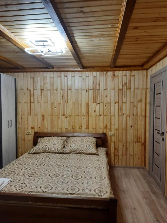a bed in a room with wooden walls and a ceiling at Дух лісу in Yaremche