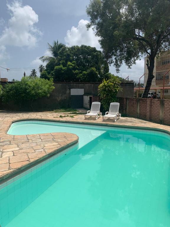 a swimming pool with two white chairs in a yard at Chalé em Nossa Senhora da Conceição in Paulista