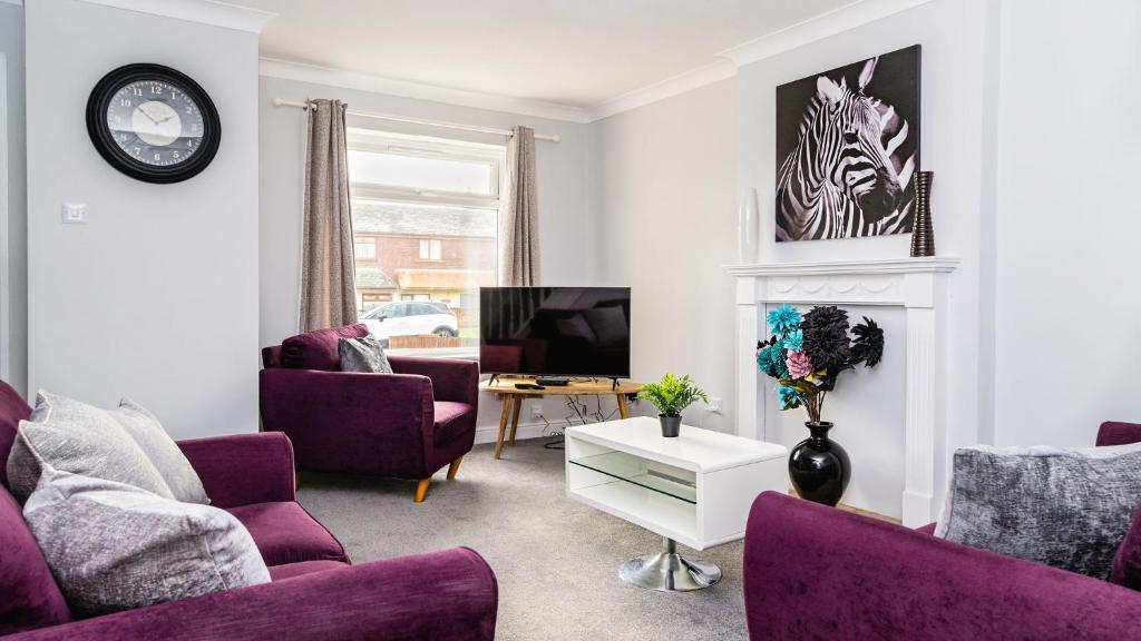uma sala de estar com cadeiras roxas e uma televisão em Mill Charm em Barrow in Furness